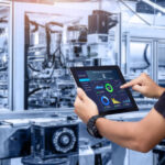 Hands holding tablet on blurred automation machine as background